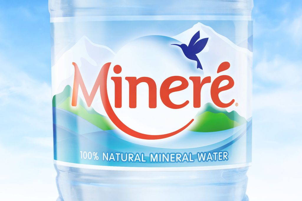 Mineré mineral water packaging design close-up showing new label with mountain landscape and hummingbird logo.